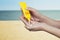 Woman applying sunscreen on her hand with sea background. SPF sunblock protection concept. Travel vacation