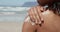 Woman applying sunscreen on shoulders at beach in the sunshine 4k