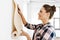 woman applying wallpaper to wall at home