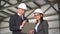 Woman approves the project. Young man and woman in helmets with documents at a construction site. Bosses in suits are