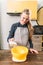 Woman in apron adds sugar into bowl, dough making