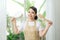 Woman in apron in hand frying pan and kitchen spatula near big window