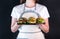 Woman in apron holding in her hands a tray with 5 burgers with different fillings