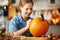 Woman in apron painting Halloween pumpkin with paint brush in hand