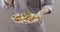 A woman in apron pins with a fork quail eggs, chicken fillet in a plate with salad with quail eggs, chicken fillet