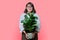 Woman in apron with potted plant, on pink background