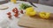 Woman in an apron puts a yellow pepper paprika on cutting wooden board. Background with ingredients for cooking salad