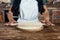 Woman in apron rolling pizza dough on wooden board