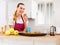 Woman in apron tasting freshly baked sweet cupcakes in kitchen