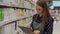 Woman in an apron working in a supermarket. A female employee writes on a tablet to inventory products in a grocery