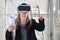 Woman architect or construction engineer wear virtual reality glasses and helmet and touch screen inside a building site with