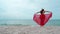 Woman with arms spread in a red dress on the sea beach with wind blow