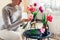 Woman arranges bouquet of tulips flowers at home. Housewife enjoys blooms in vases on table. Interior and decor