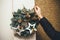 Woman arranging christmas wreath on the outside wall