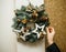 Woman arranging christmas wreath on the outside wall