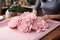 Woman arranging vibrant peony bouquet on rustic craft paper table in natural light-filled room