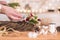 Woman artisan making Christmas holiday wreath on a table among by New Year& x27;s decor