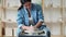 Woman artisan sitting on chair and crafting clay vessel on wheel during work in spacious professional pottery