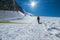 Woman ascending Mont Blanc Monte Bianco summit 4,808m dressed red mountaineering clothes walking by snowy slopes with blue sky