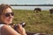 Woman on asian wildlife safari. Lady taking a photo of herd of elephants with her camera.