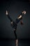 Woman athlete gymnast performing acrobatic elements on a black b