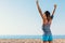 Woman athlete raising arms at sea.