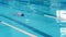 Woman athlete swimmer swims using backstroke technique in pool. Enjoying swimming and water sports.