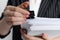 Woman attaching documents with metal binder clip on grey background, closeup