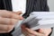 Woman attaching documents with metal binder clip on grey background, closeup