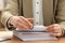 Woman attaching documents with metal binder clip at table in office, closeup