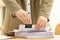 Woman attaching documents with metal binder clip at table in office, closeup