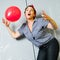 Woman attractive joyful senior woman playing with red balloon inside her apartment just near fireplace