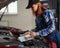 Woman auto mechanic doing engine diagnostics using laptop.