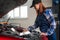 Woman auto mechanic doing engine diagnostics using laptop.