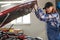 Woman auto mechanic opens the hood of a car in a car service.