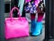 Woman in autumn or spring in a bright coat and a pink big bag. Blue boots, boots. Fashionable bag close-up in female hands.