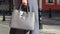 Woman in autumn or spring in a gray coat and gray big bag. Fashionable bag close-up in female hands.