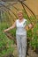 The woman of average years shows plants of tomatoes in the greenhouse