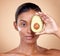 Woman, avocado and cream for face skincare, natural beauty or vitamin c benefits on studio, brown background. Young