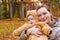 Woman with baby in arms, posing in autumn Park