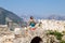 Woman with baby sit on rock and look at the mountains, rear view. Kotor, Montenegro