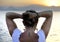 Woman with back seahorse tattoo standing alone looking at sea horizon