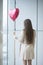 Woman with back to camera holding heart shaped balloon