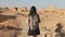 Woman with backpack explores ancient desert ruins. Beautiful European tourist walks on rocks and sand. Masada Israel 4K.
