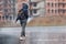 A woman with a backpack and a hood runs in the pouring rain