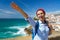 Woman with a backpack makes a welcome hand gesture on the ocean