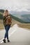 A woman with a backpack and a road stretching into the distance