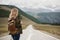 A woman with a backpack and a road stretching into the distance