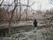 Woman with backpack standing in abandoned woods place. Person hiking on trail in wild forest on a spring summer autumn day. Solo