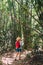 Woman with backpack on trek through jungle stopping looking bamboo forest top branches